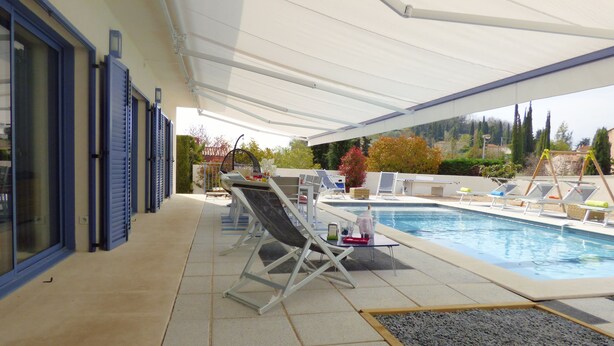An outdoor pool area with lounge chairs and a covered patio.