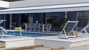 A poolside area with lounge chairs, a table, and chairs.