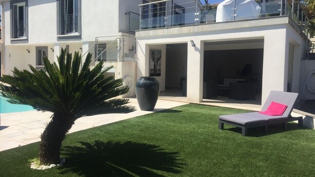 Una casa moderna con piscina, un porche cubierto y una silla de descanso.