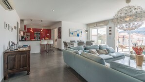 Een moderne woonkamer met een grote bank, een eethoek en een keuken.