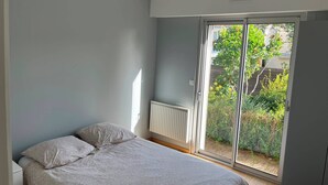 Et soveværelse med seng, radiator og en skydedør til en have.