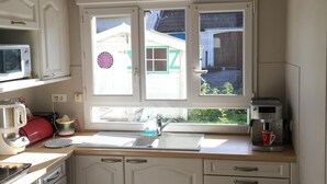 Eine kleine Küche mit weißen Schränken, einer Spüle, einer Kaffeemaschine und einem Mülleimer.
