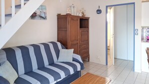 Een woonkamer met een gestreepte bank, een houten kast en een trap.