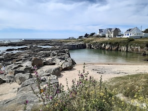 A coastal landscape with rocky terrain, a sandy beach, and a body of water.