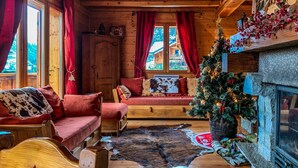 Een gezellig houten interieur met een open haard, een kerstboom en een vachtkleed.