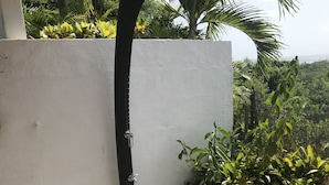 A black outdoor shower with a white wall and plants around it. - Sainte-Anne, typical villa for 4-6 people Sea view, directly on the beach. (Sainte Anne)
