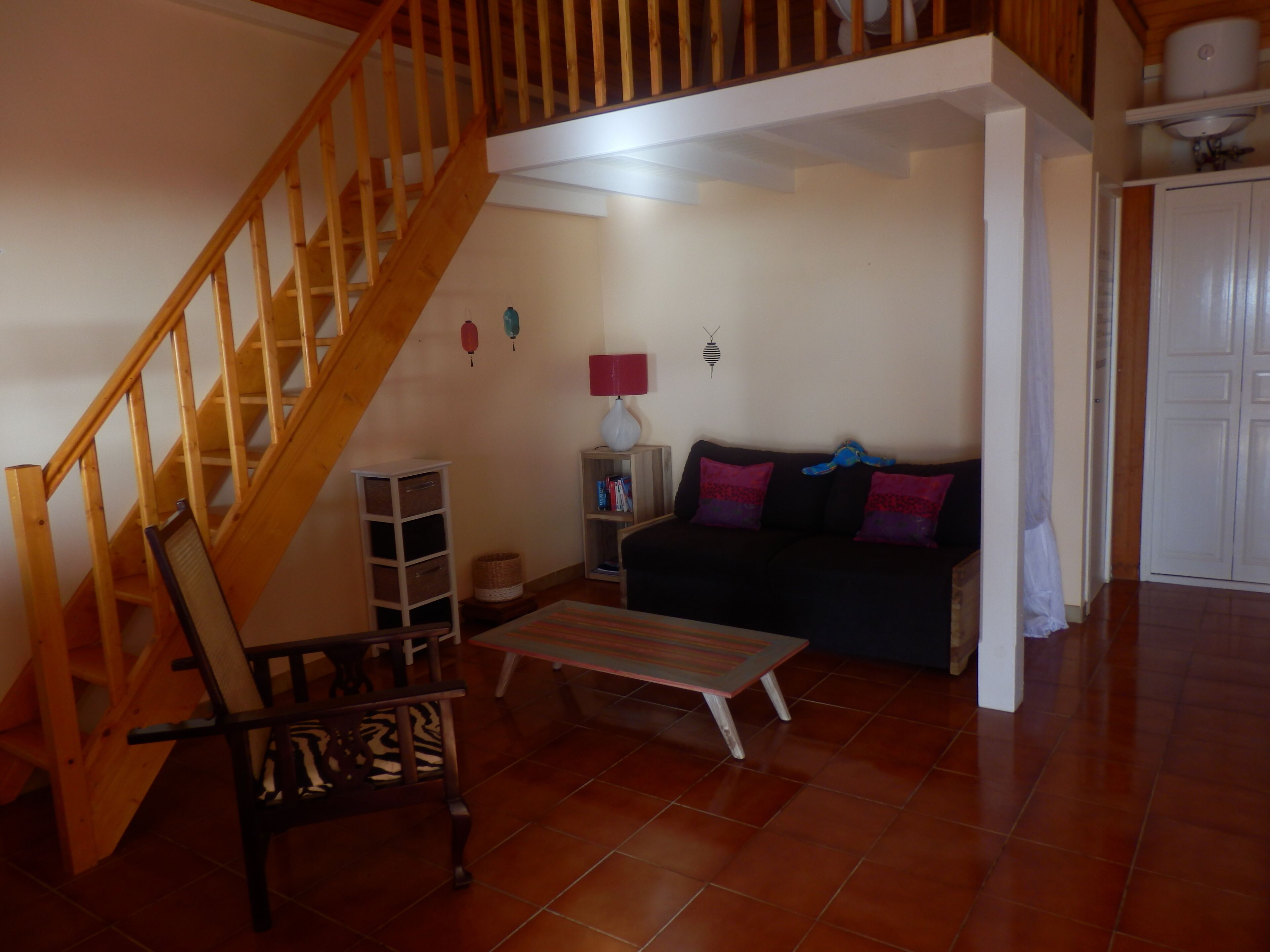 A living room with a wooden staircase, a sofa, a coffee table, and a bookshelf.