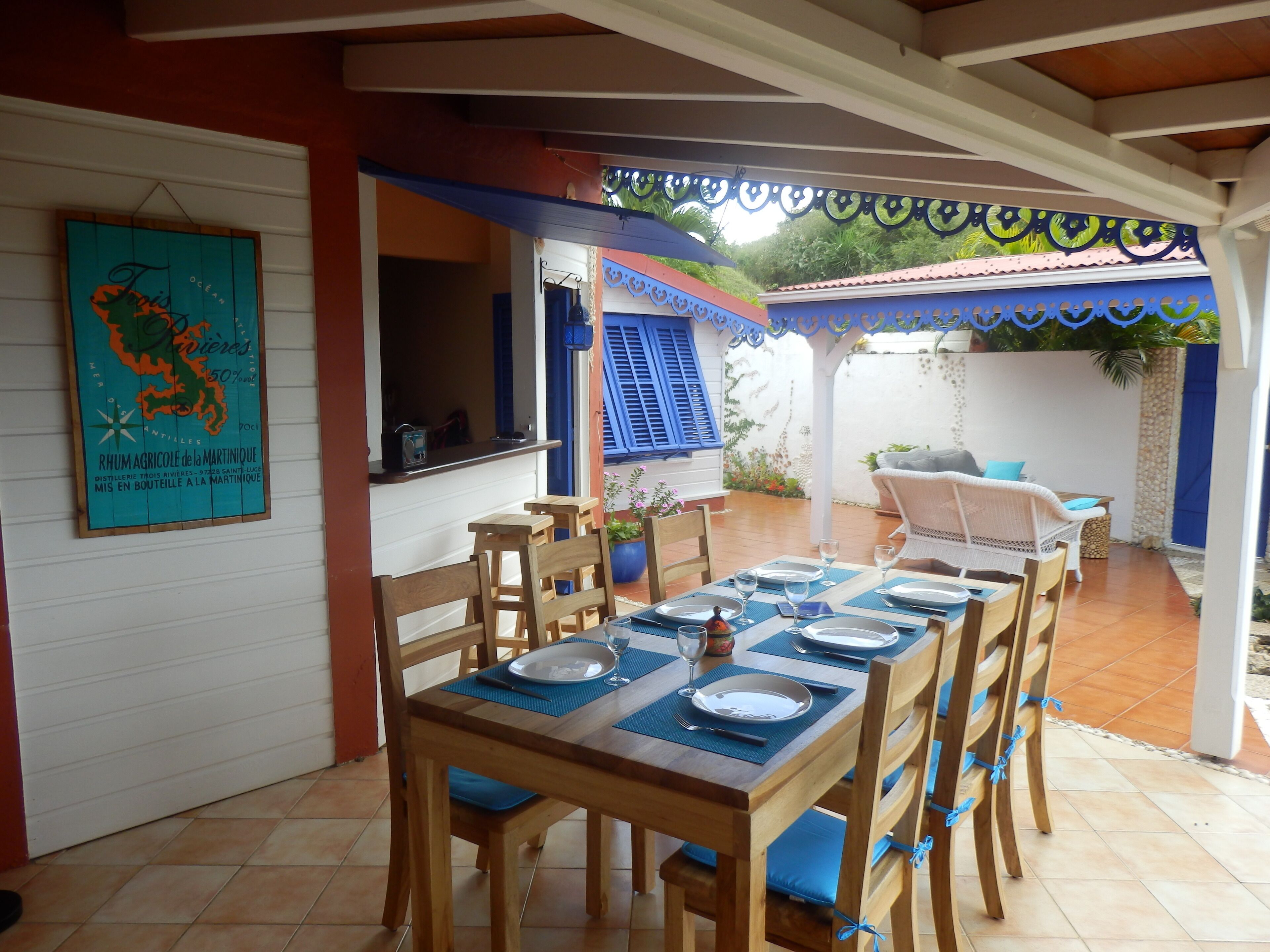 Comedor con una mesa dispuesta para cuatro, sillas de madera y un camino de mesa azul.