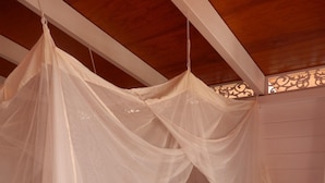 A bed with a canopy, a bedside table with a lamp, and a patterned bedspread. - Sainte-Anne, typical villa for 4-6 people Sea view, directly on the beach. (Sainte Anne)