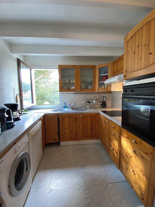 A modern kitchen with wooden cabinets, a built-in oven, and a washing machine.