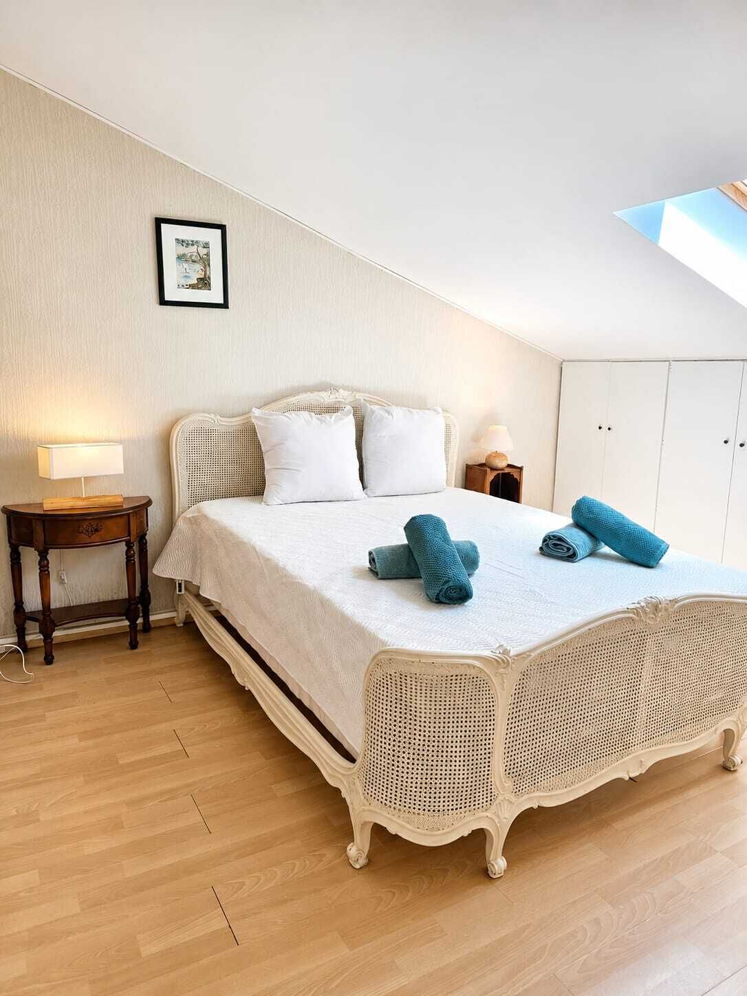 A bedroom with a large bed, a bedside table, a lamp, and a wardrobe.