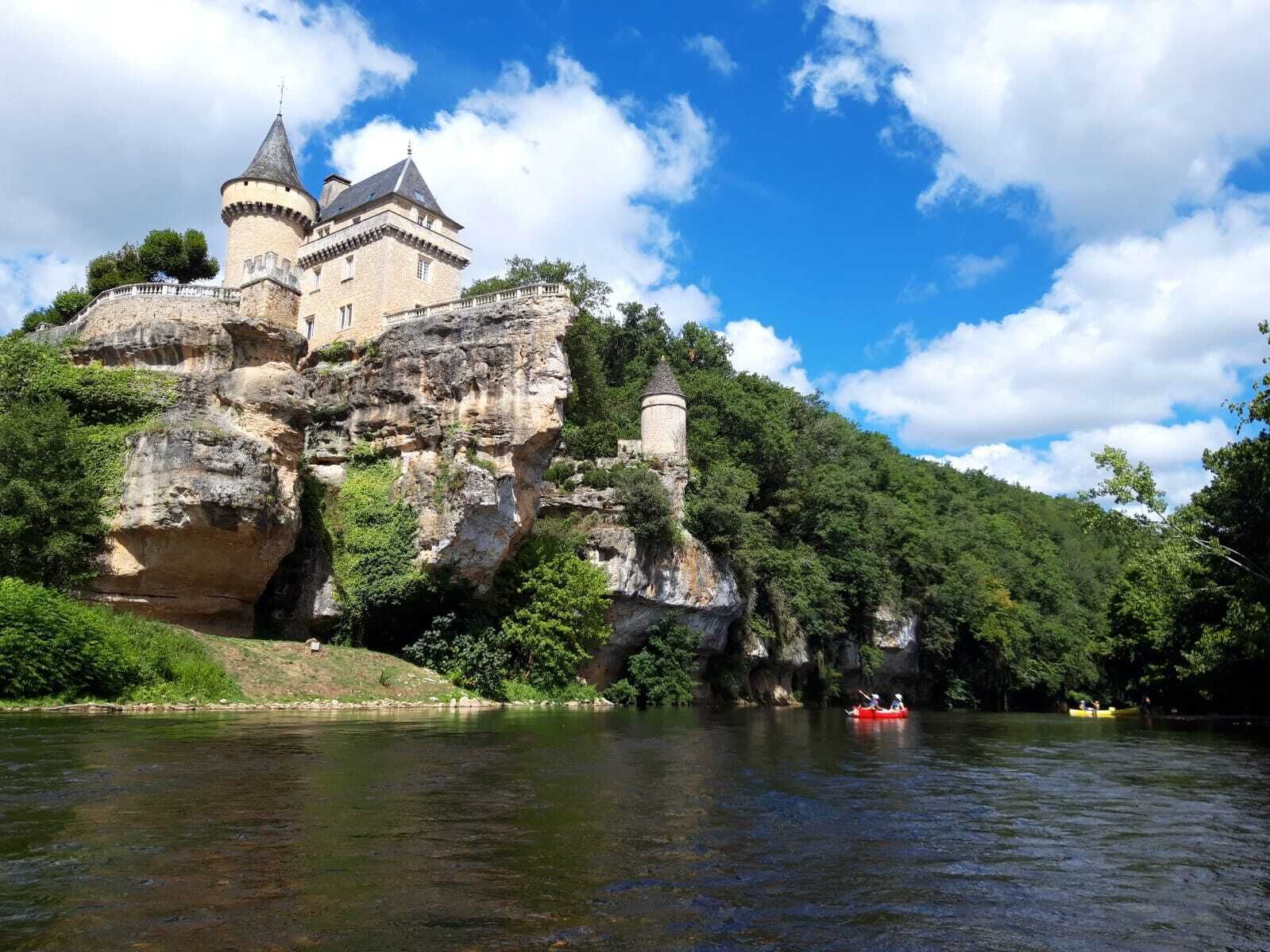 Un castillo construido sobre un risco con vista a un río.