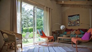 Un salon spacieux doté d’une grande porte-fenêtre coulissante donnant sur un jardin, d’un ensemble de canapés et d’un lampadaire.