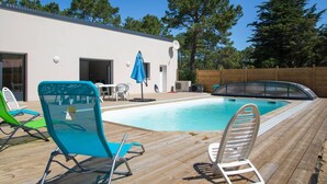 Une piscine avec des chaises longues et une terrasse en bois.