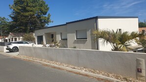 Une maison moderne à deux étages, avec une façade blanche, un garage et une allée.
