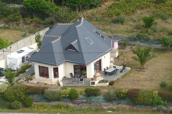 A house with a sloped roof, a patio with outdoor furniture, and a small garden area. - Contemporary house at the foot of the Trézien lighthouse. Magnificent beach 500m away. (Plouarzel)