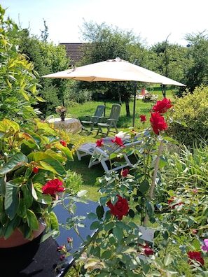 A garden with a patio area, including a table, chairs, and a large umbrella.