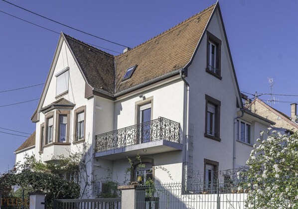Ein zweistöckiges Haus mit Balkon, einem Fenster und einer kleinen Grünfläche.