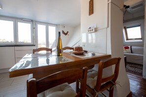 Ein Essbereich mit einem Holztisch und Stühlen, einer Weinflasche und einem dekorativen Vogel an der Wand.