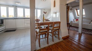 A modern kitchen with white cabinets, a dining area with wooden chairs, and a view through large windows. - At the gates of Strasbourg charming apartment in lush greenery 4 per. (Eckbolsheim)