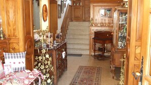 Un vaste salon agrémenté d’un magnifique escalier, de meubles en bois et d’un lustre.