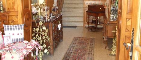A spacious living room with a grand staircase, wooden furniture, and a chandelier.