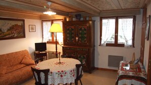 Un salon chaleureux avec une table ronde, un canapé, un meuble et un téléviseur.