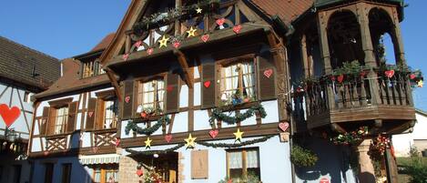 A traditional half-timbered building with a balcony and a bell tower, decorated with festive garlands and ornaments.