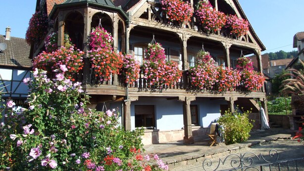 Un bâtiment traditionnel doté de nombreux balcons ornés de jardinières suspendues.