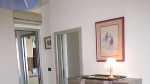 Une pièce avec un meuble en bois, une lampe et un tableau encadré accroché au mur.