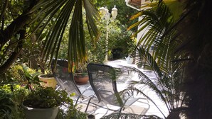 A garden patio with a metal chair, potted plants, and a street lamp. - Charming house, in a green setting, on the Landaise Coast (Labenne)