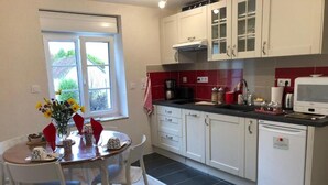 A modern kitchen with white cabinets, a black countertop, and a window with a view of greenery.