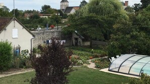 A rural setting with a stone house, a small garden, and a greenhouse.