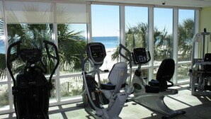 Ein Fitnessraum mit Cardiogeräten und Blick auf den Strand.