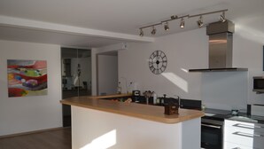 A modern kitchen with a central island, stainless steel appliances, and a wall clock.