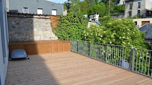 A wooden deck with a stone wall and a metal railing.