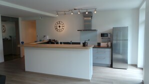 A modern kitchen with a central island, stainless steel appliances, and a clock on the wall.