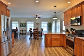 Enjoy cooking in this well-equipped kitchen with a central island, refrigerator, microwave, and stove.