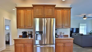Una cocina moderna con armarios de madera, un refrigerador de acero inoxidable y una cafetera.