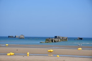 A beach with yellow buoys and concrete structures in the water.