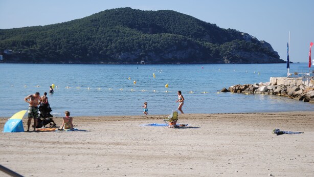Una spiaggia con persone, una sedia e una bandiera.