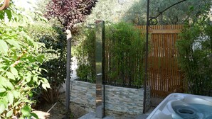 Una vasca idromassaggio in un giardino con un recinto in legno e un muro in pietra.