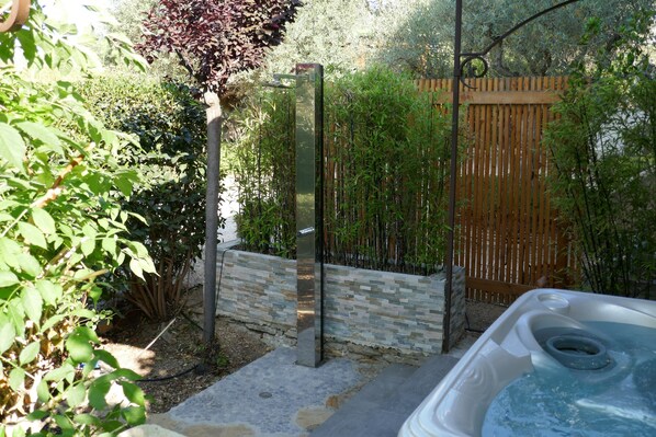A hot tub in a garden with a wooden fence and stone wall.