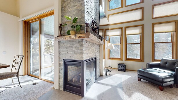 A spacious living room with a stone fireplace, large windows, and a comfortable seating area. - Snowcreek #880 3 Bedroom Condo by RedAwning (Mammoth Lakes)