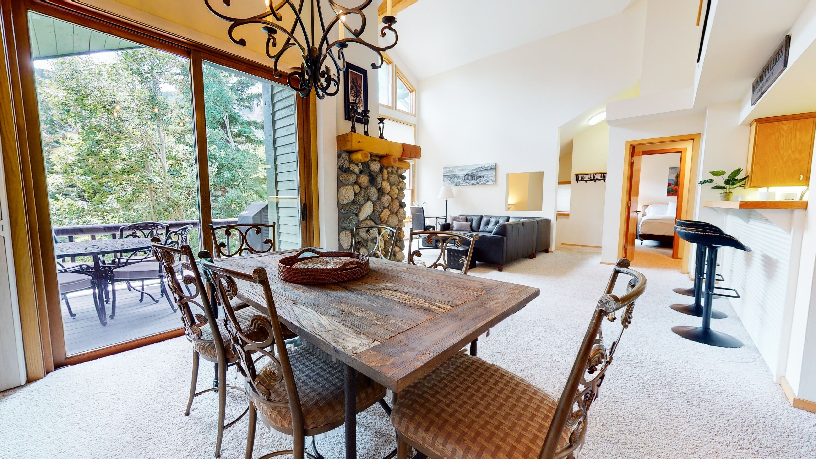 A spacious living room with a large wooden table, comfortable seating, and a stone wall.