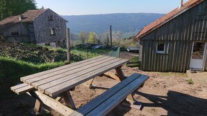 Eine ländliche Außenansicht mit einem Holztisch, einem Steinhaus und einem Holzschuppen.