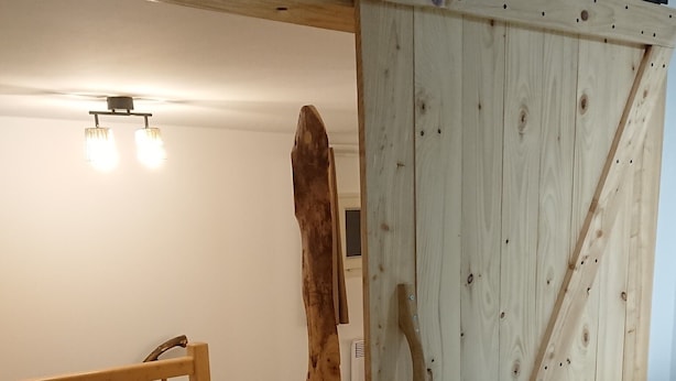 Eine Holzbeschreibung mit einer großen Tür, einer Holztreppe und einer Leuchte an der Decke.