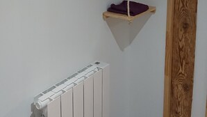 Ein Zimmer mit einer weißen Heizung, Holzbalken und einem hängenden Regal mit einer Flasche.