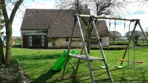 Een schommel in een gazon met een huis op de achtergrond.