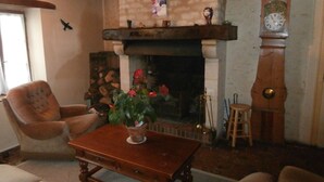 Een gezellige woonkamer met een open haard, een houten salontafel en een klok aan de muur.